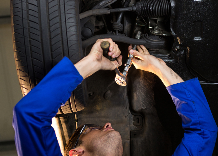 Técnico especializado realizando mantenimiento en el sistema de suspensión de un vehículo. Con precisión y herramientas adecuadas, garantiza la seguridad y el rendimiento óptimo del automóvil, resaltando la importancia del servicio mecánico de calidad.